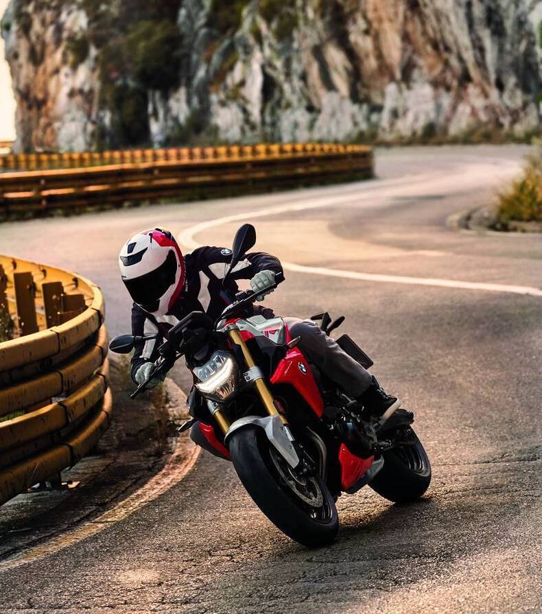 Mand på rød BMW motorcykel kører på snoet bjergvej