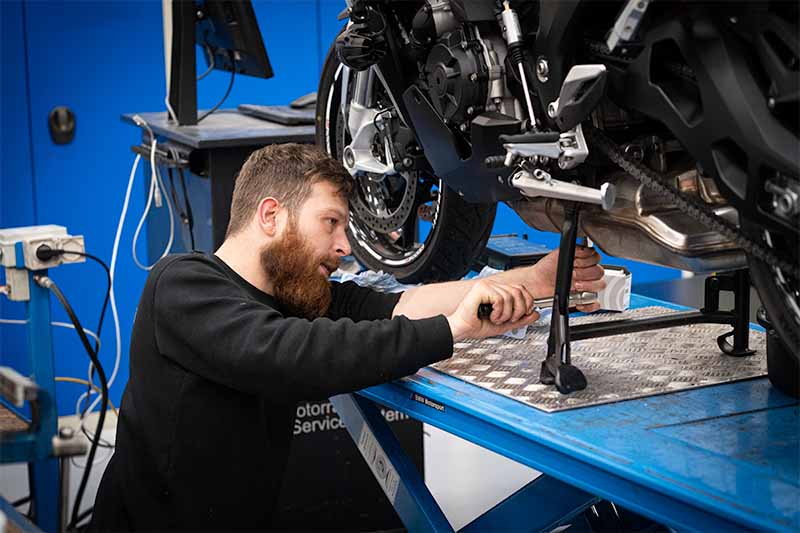 Mekaniker arbejder på BMW motorcykel på lift