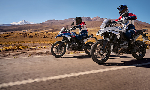 To motorcykler kører på vej i stenet bjerglandskab