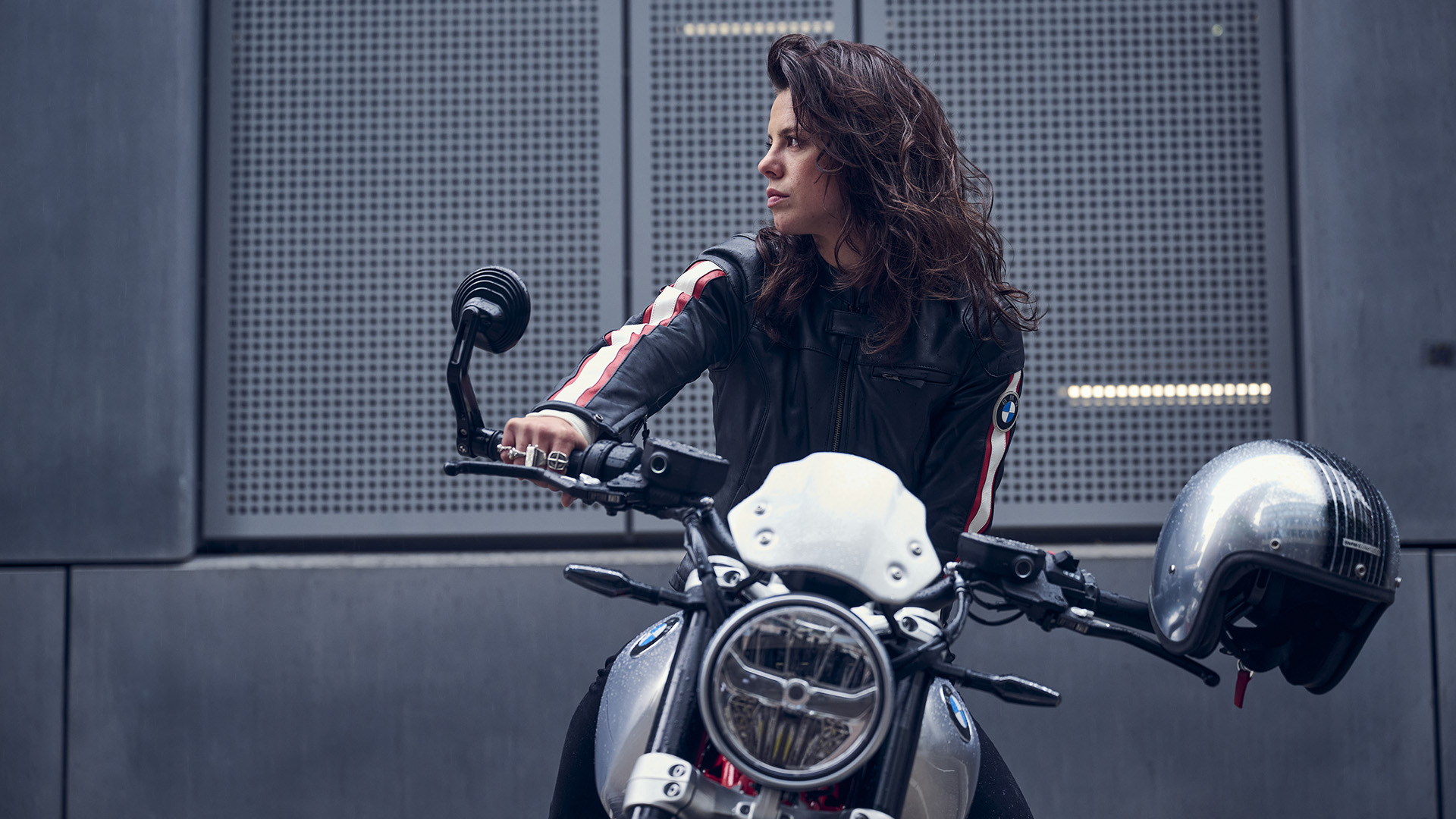 Kvinde på motorcykel foran betonvæg