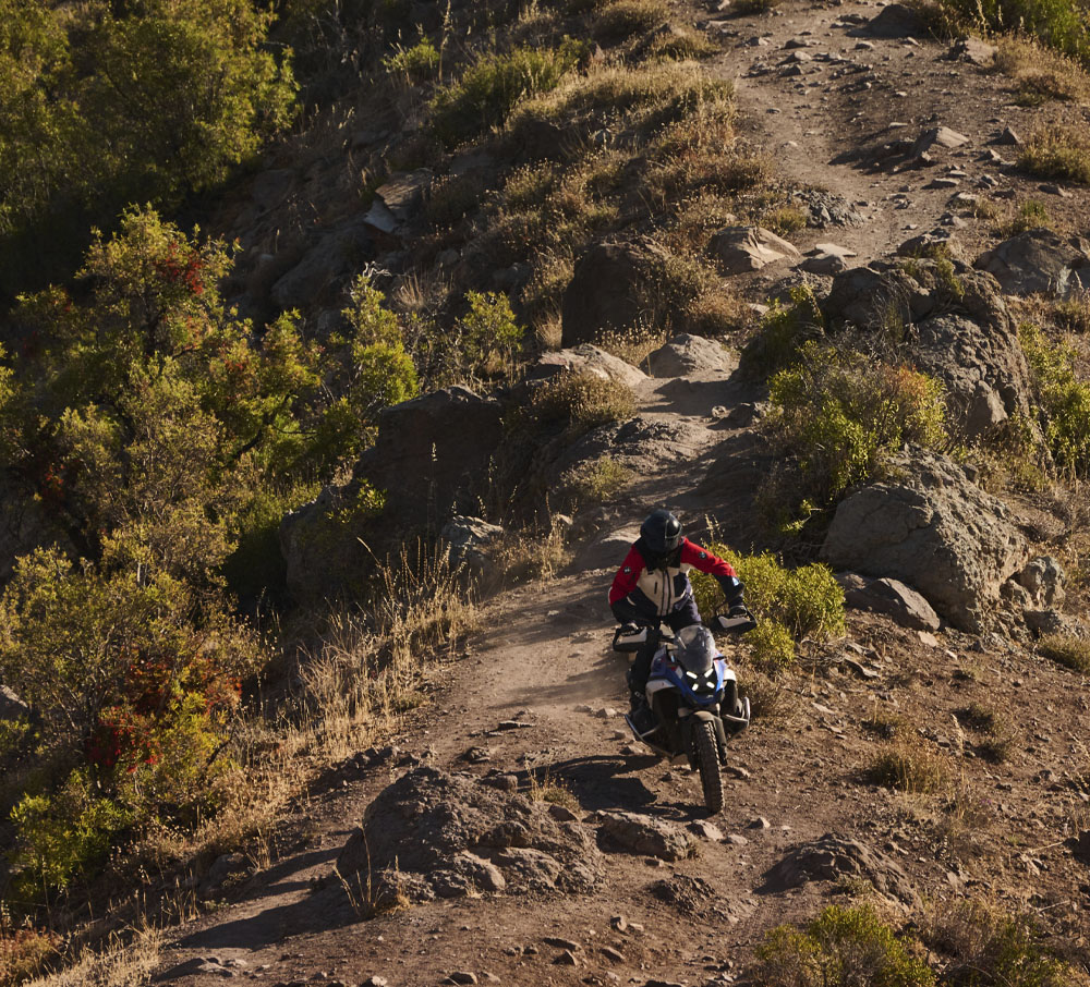 Mand på blå BMW motorcykel på vej ned af stenet bjerg 