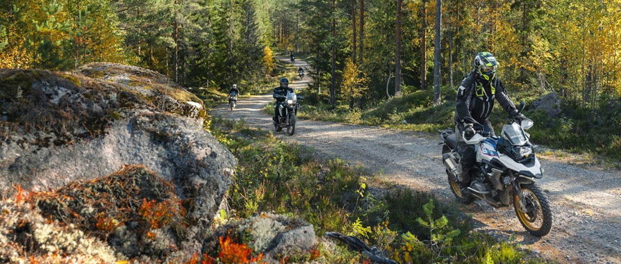 Motorcykler kører offroad på grusvej gennem skov